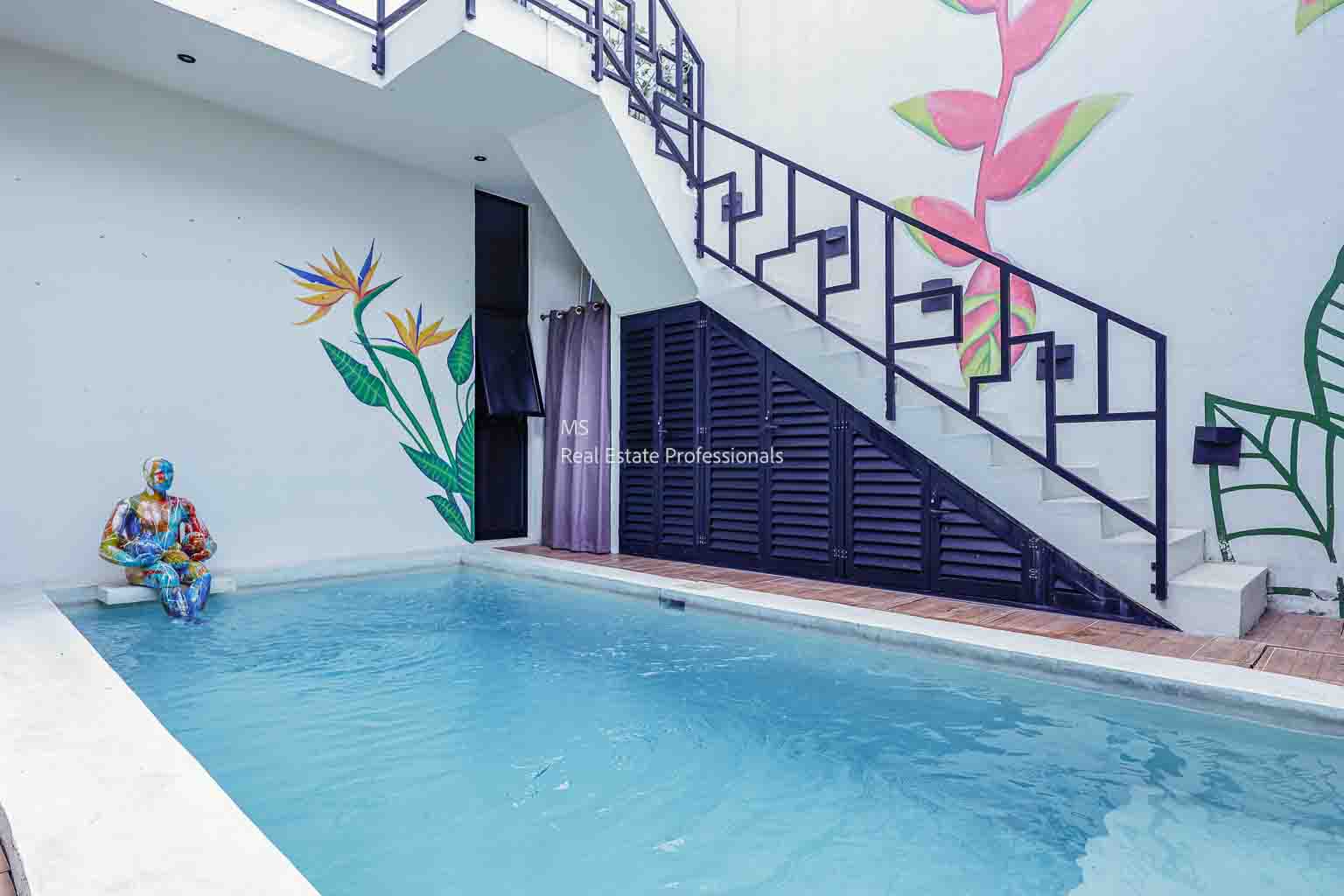 A swimming pool beside a staircase with floral wall art.