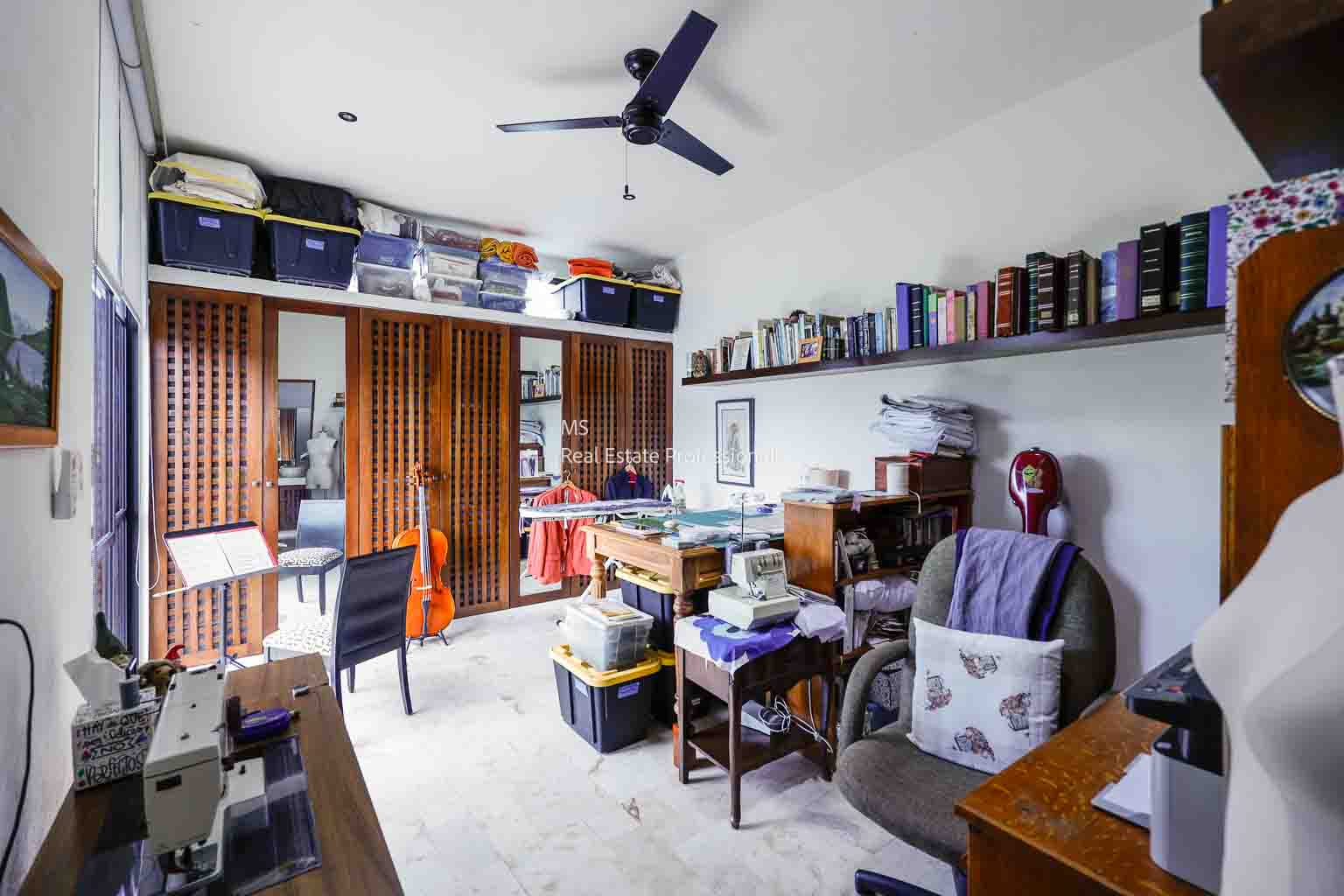 Cozy home office with bookshelves and a ceiling fan.