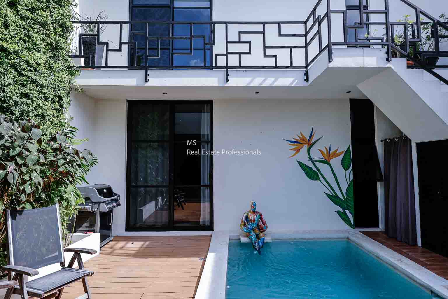 A modern patio with a small pool, decorative wall painting, and a Buddha statue.