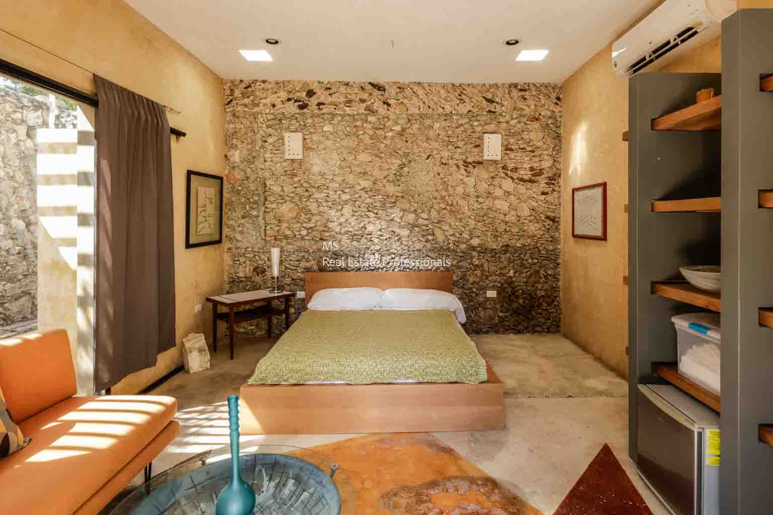 Cozy rustic bedroom with stone wall and simple decor.