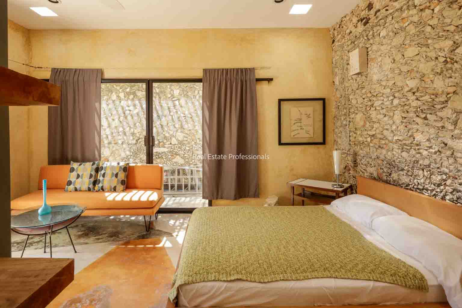 Cozy bedroom with stone accent wall and large windows.
