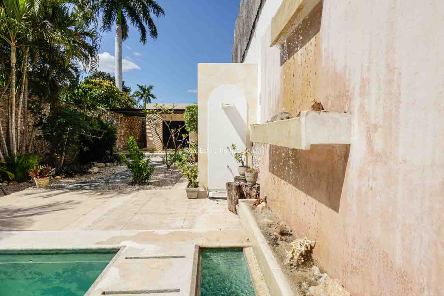 Outdoor space with a small pool and rustic stone walls under a clear sky.