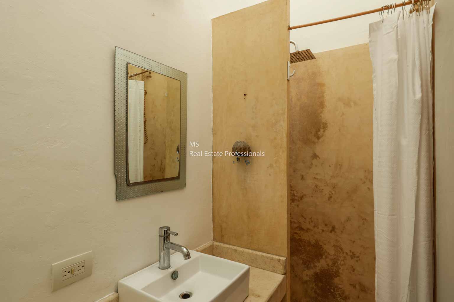Minimalist bathroom with a sink, mirror, and shower area.