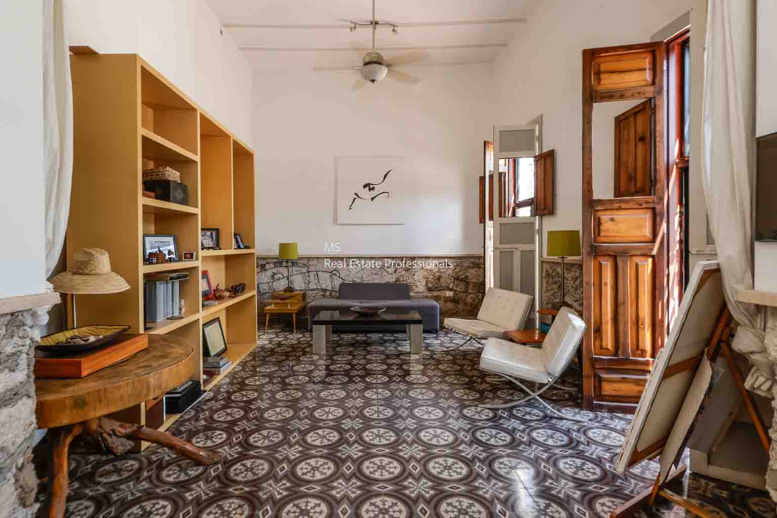 Cozy living room with patterned floor tiles and wooden furniture.