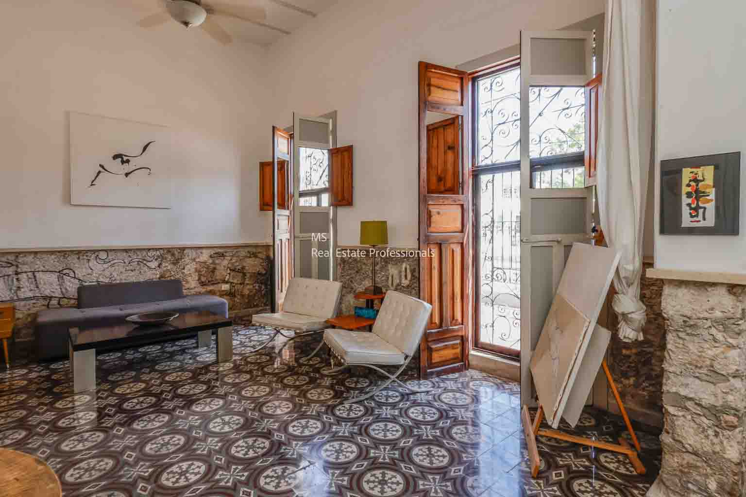 Cozy vintage living room with patterned tile floor and wooden shutters.