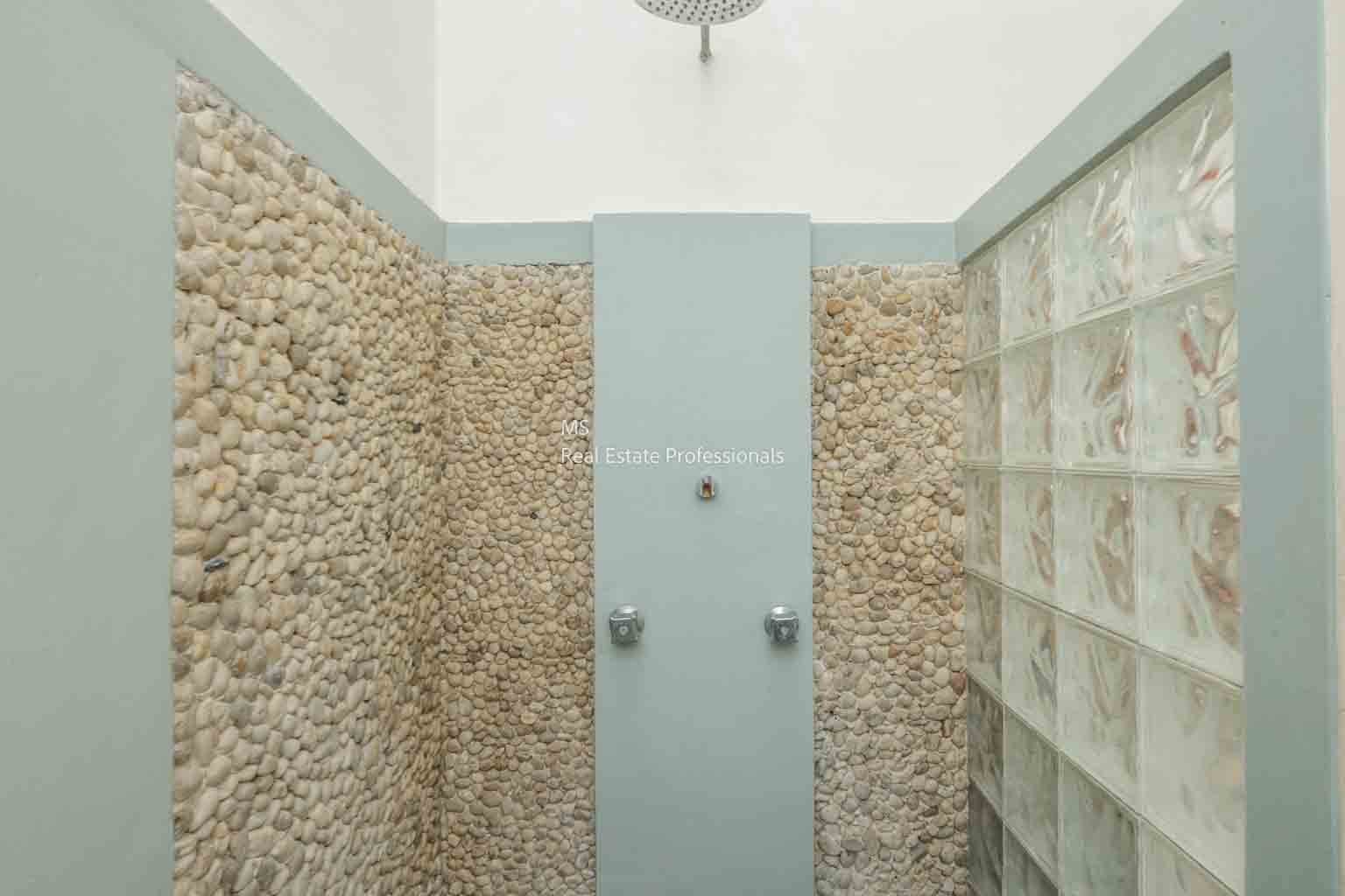 Modern outdoor shower with stone walls and glass block accents.