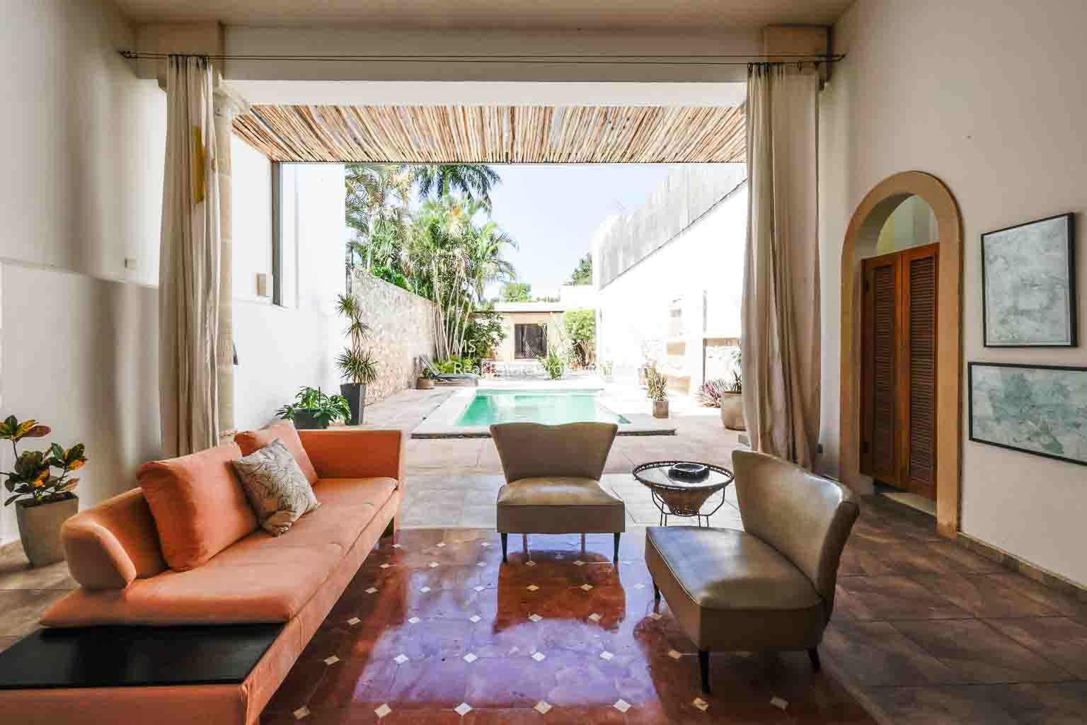 Stylish living room with cozy seating and a view of a sunny outdoor pool area.