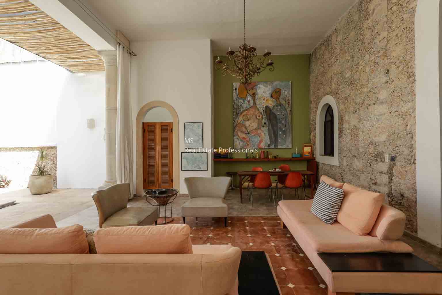 Cozy living room with beige sofas, artwork, and stone walls.