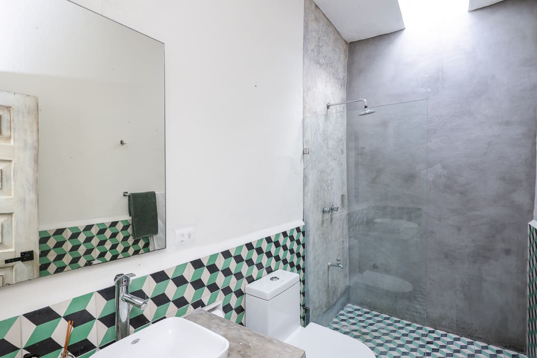 Minimalist bathroom with green checkered tiles and glass shower enclosure.