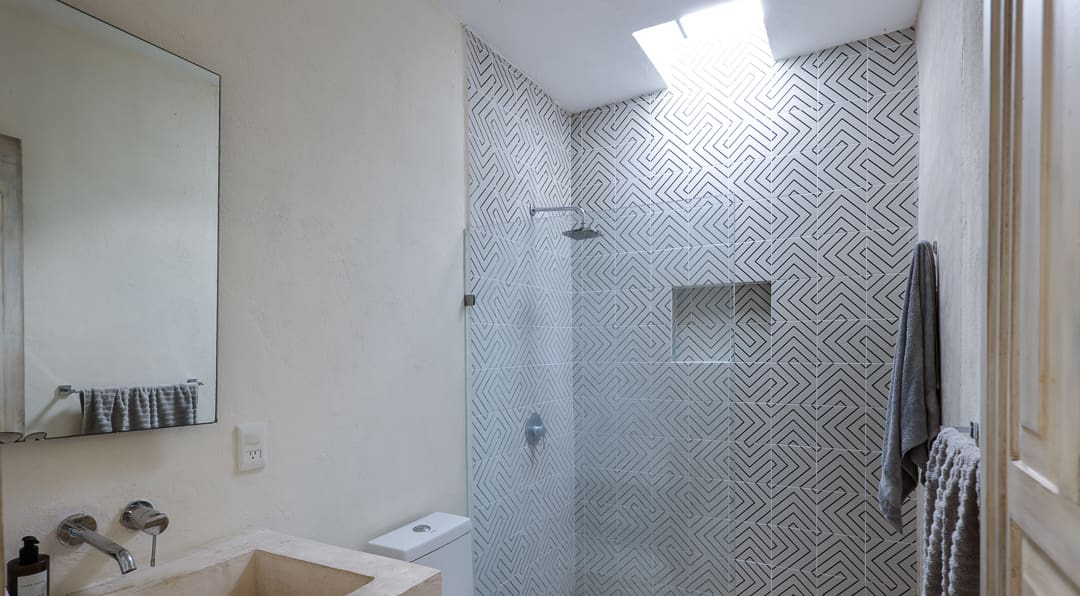 Modern bathroom with glass shower enclosure and hexagonal tile wall.