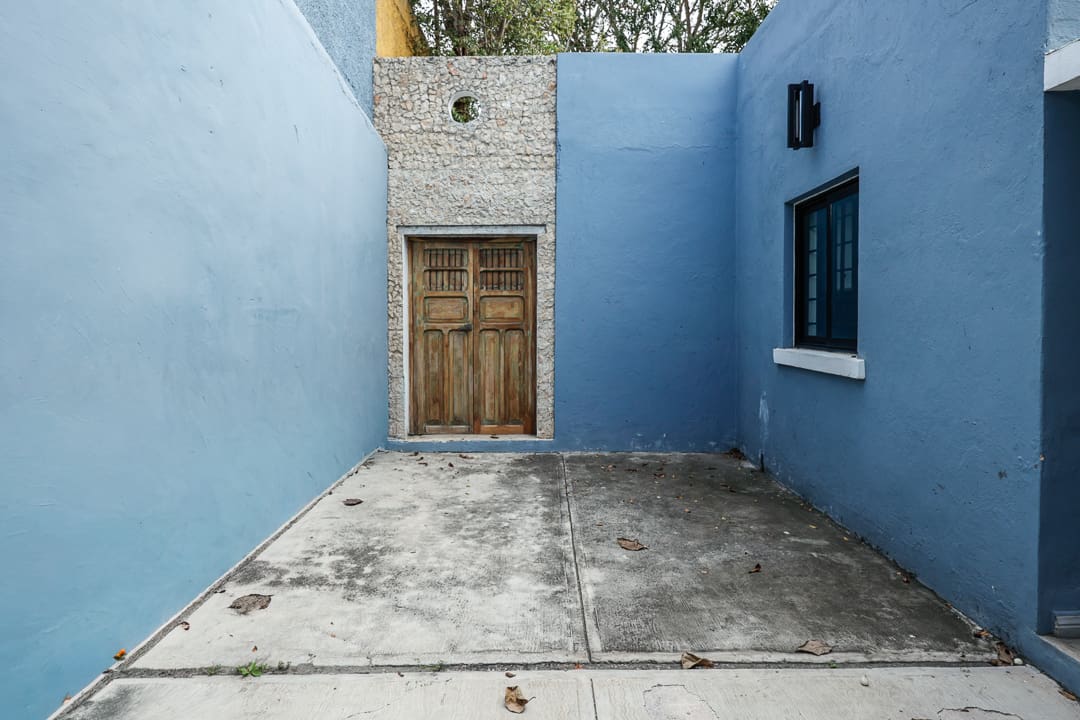 Empty courtyard with blue walls and a wooden door.