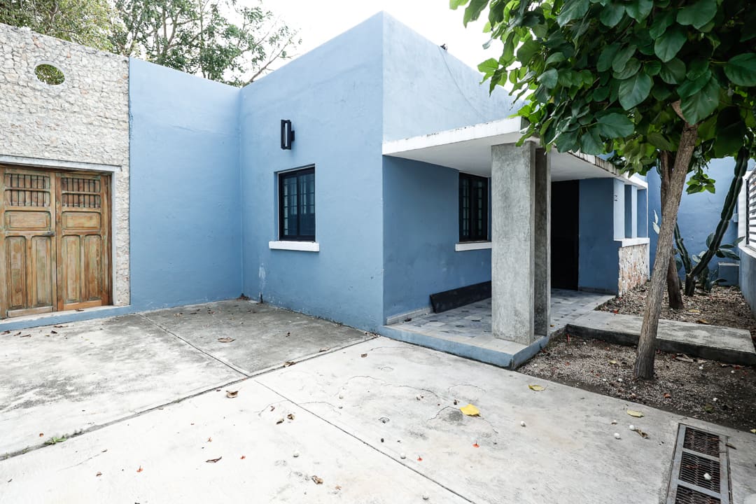Simple blue house with a concrete driveway and a small covered porch.