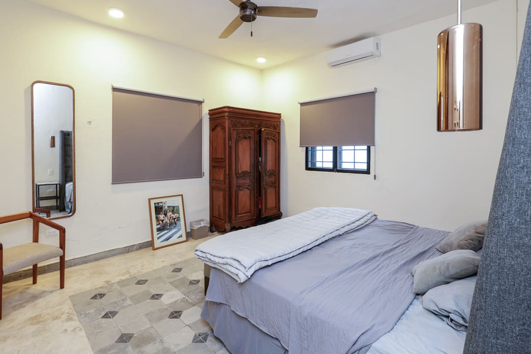 Cozy bedroom with gray bedding and wooden wardrobe.