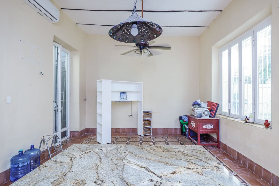 Empty room with ceiling fan and scattered debris on the floor.