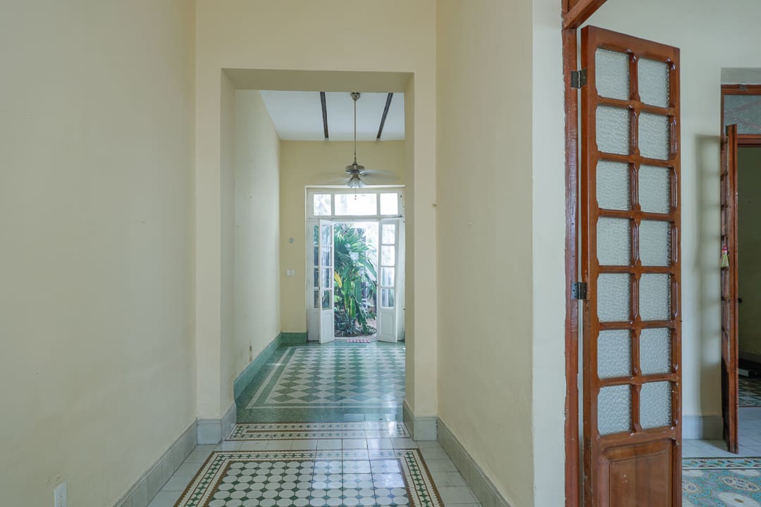 A bright hallway with patterned floor tiles and a window at the end.