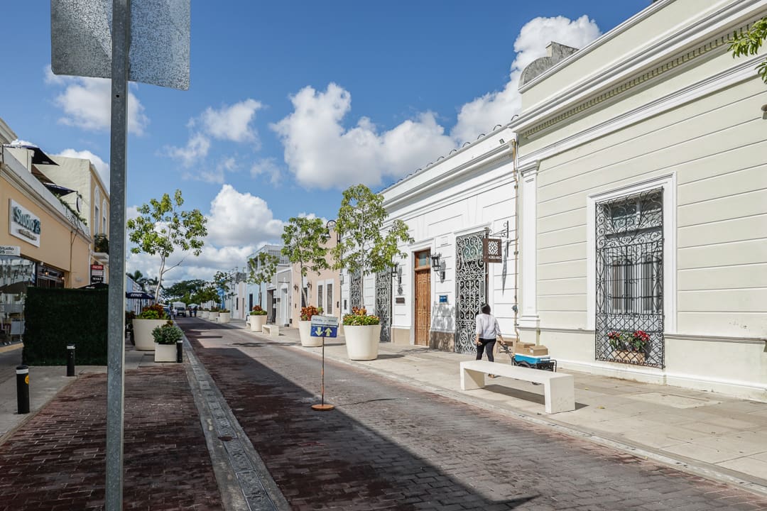 Street view of a historic white building under a blue sky with scattered clouds.