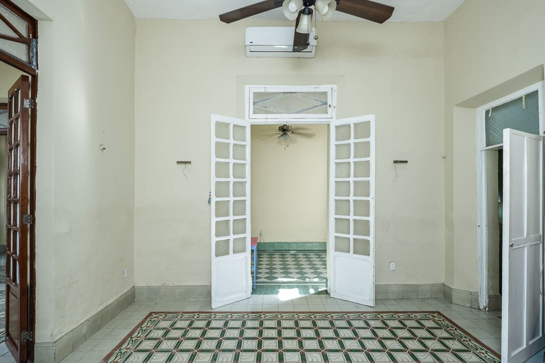 Empty room with open white French doors and ceiling fan.