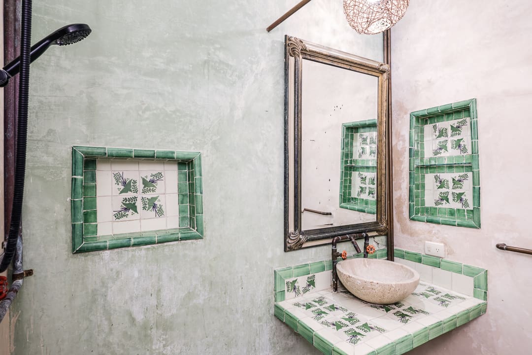 Rustic bathroom with green tiled accents and a vessel sink.