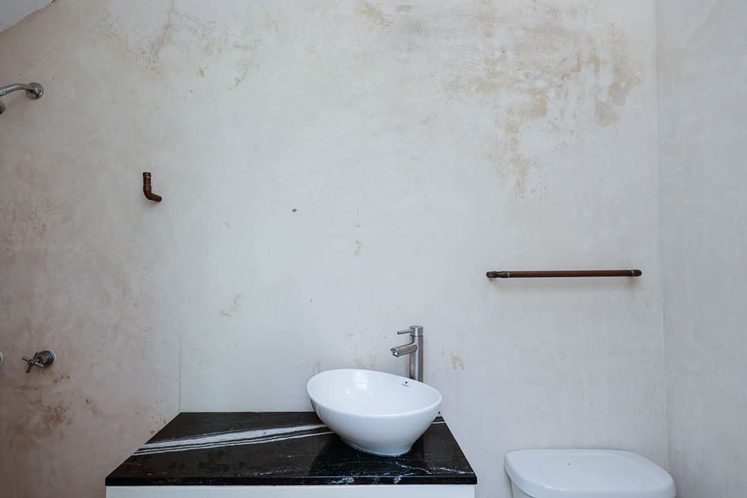 Minimalist bathroom with a modern vessel sink on a black countertop.