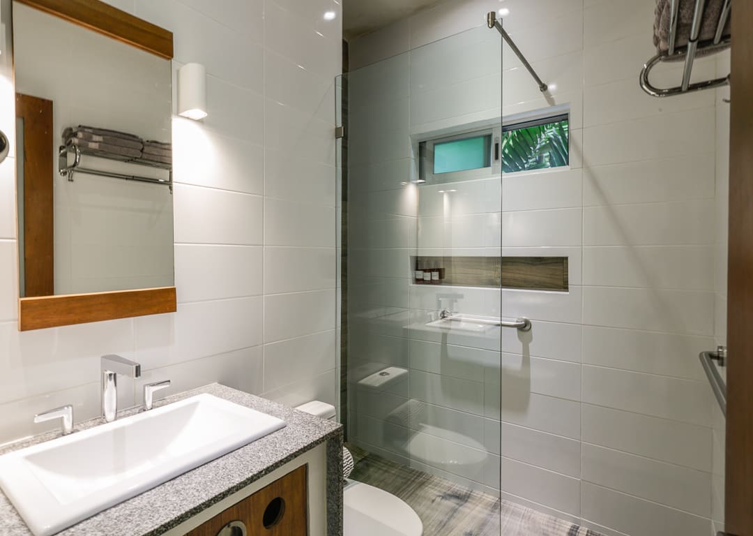 Modern bathroom with glass shower enclosure and white tiles.