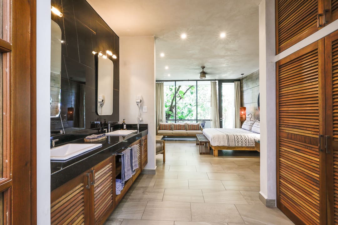 Spacious modern bedroom with an open bathroom and large windows.