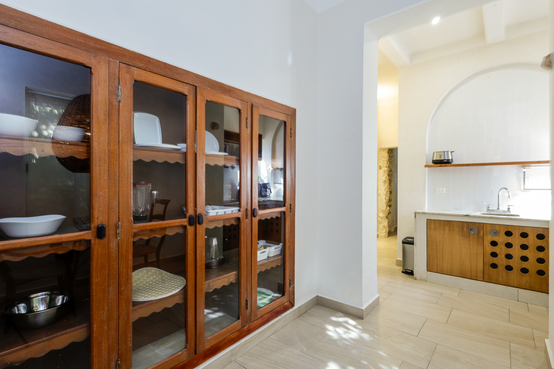 Wooden cabinet with glass doors in a bright room with tiled floor.
