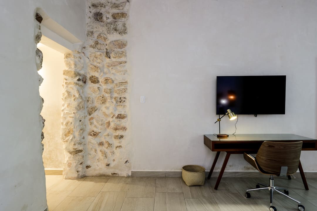 Minimalist room corner with a stone wall, wooden table, and lamp.