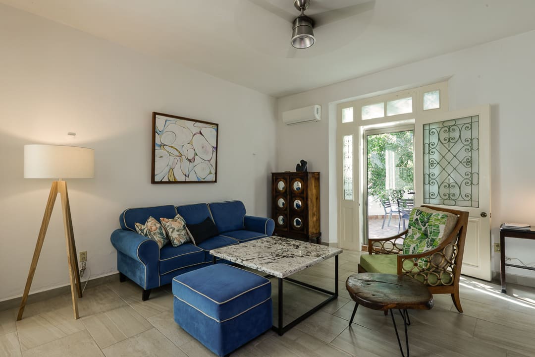 Cozy living room with blue sofa and green armchair by large windows.