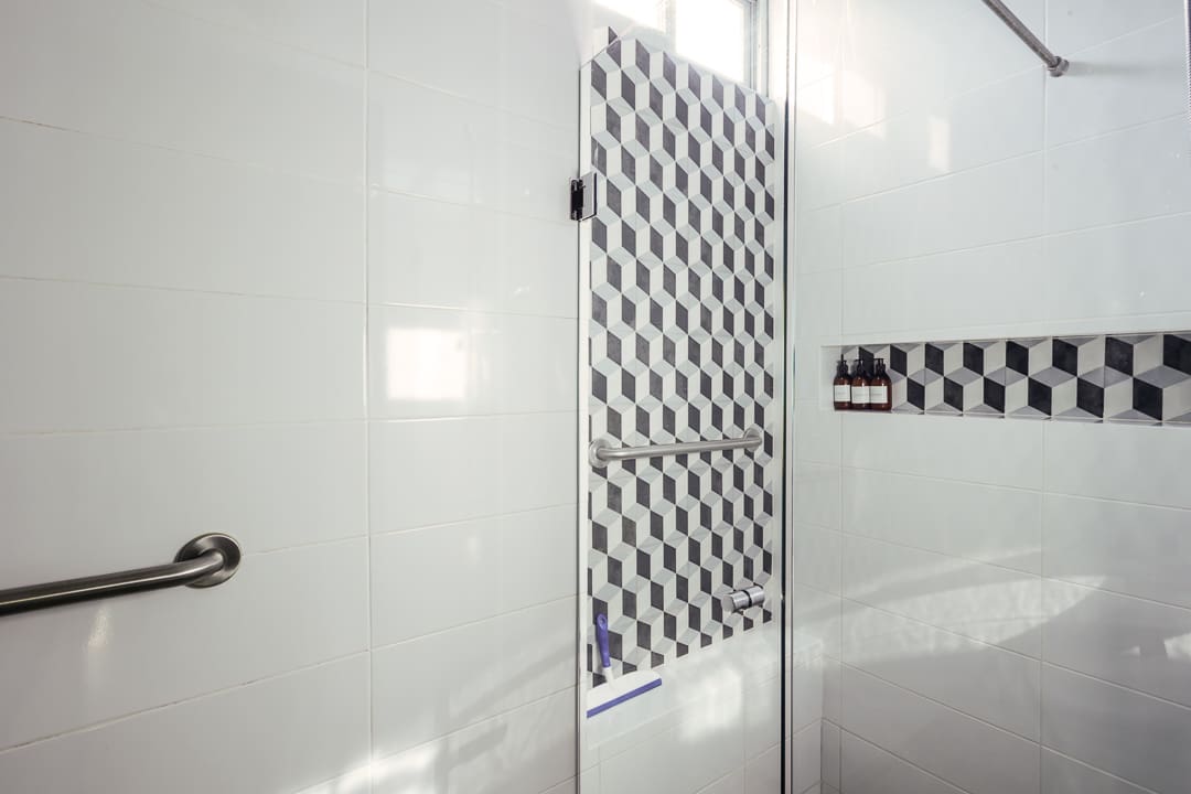 Shower door with black and white tile pattern in a bathroom.