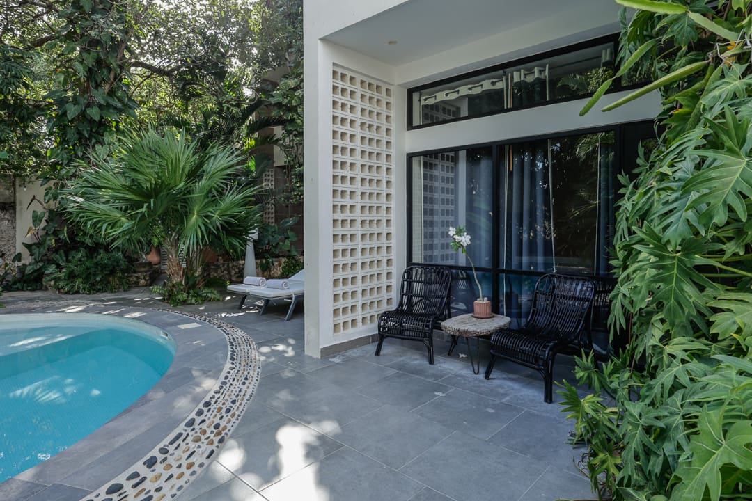 Cozy outdoor seating area beside a pool and lush greenery.