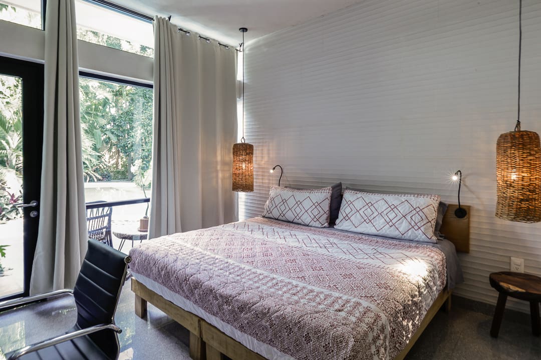 Cozy bedroom with patterned bedding and soft lighting near a window.