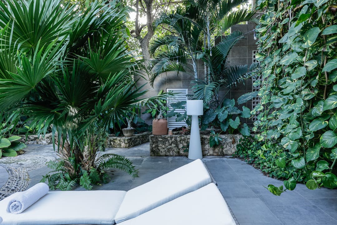Peaceful outdoor patio with greenery and comfortable lounge chairs.