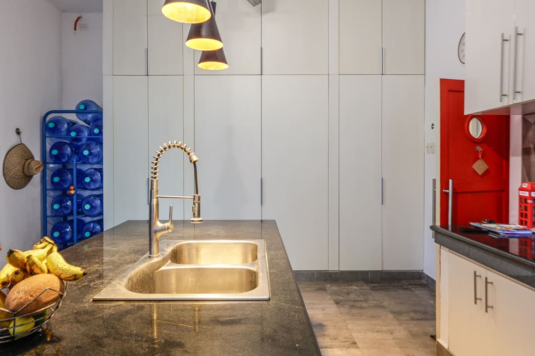 Modern kitchen sink area with brass fixtures and pendant lights.