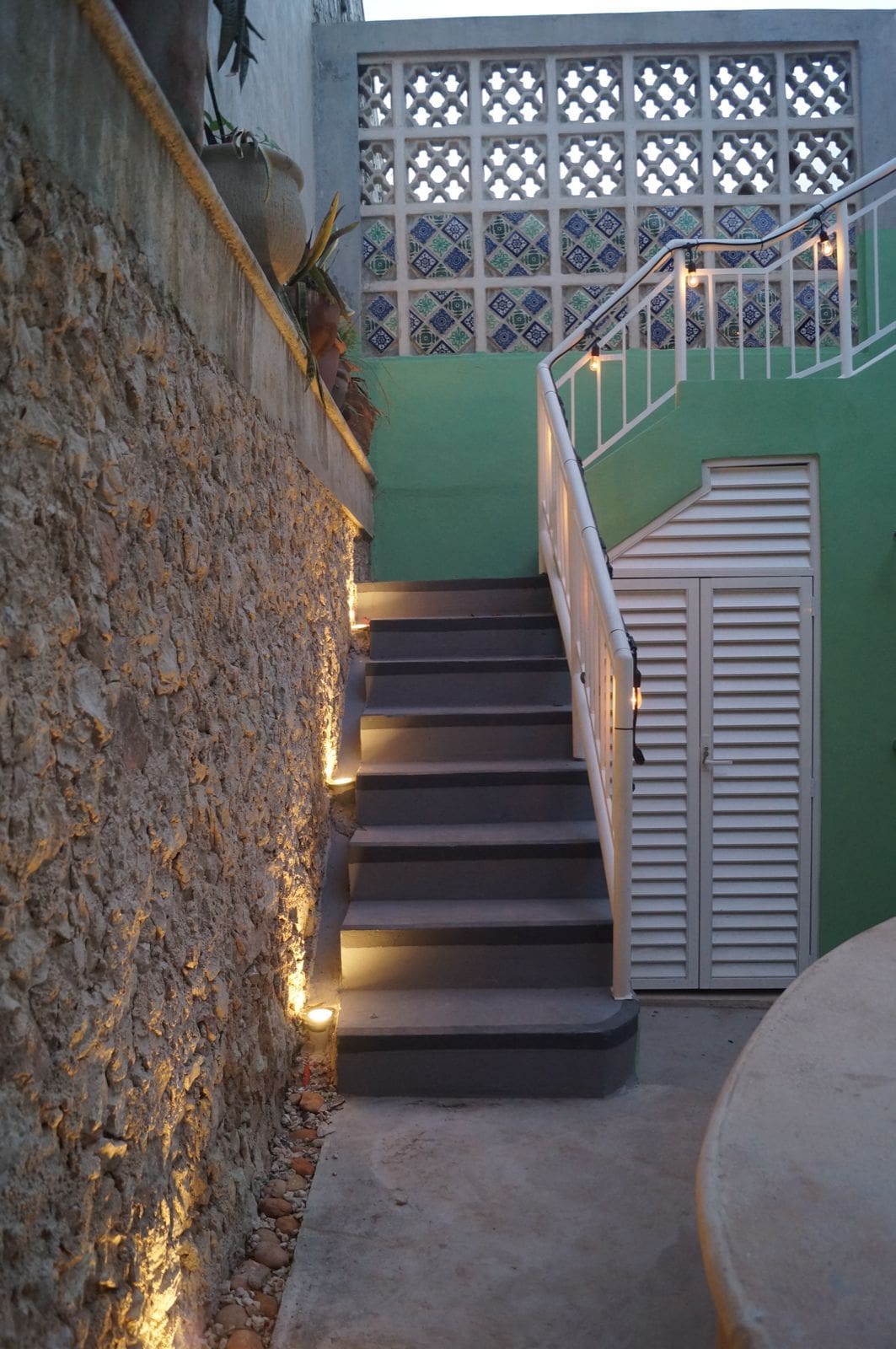 Outdoor stone stairs with warm lighting along the wall.