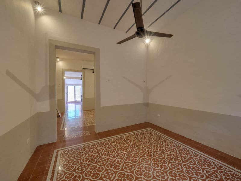 Empty room with patterned tile floor, ceiling fan, and arched doorway.