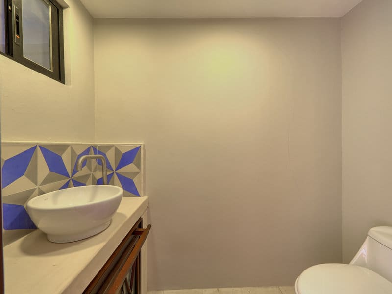 Minimalist bathroom with a decorative blue and white tile backsplash.