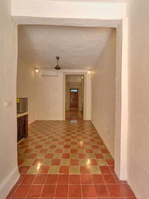 Empty narrow hallway with tiled floor and ceiling fan.