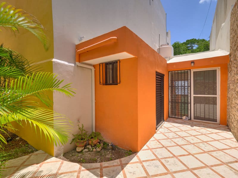 Bright orange wall contrasts with neutral building and sunny courtyard.