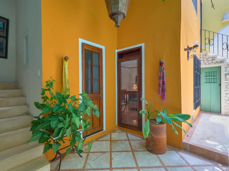 Cozy yellow hallway with plants and a wooden door.