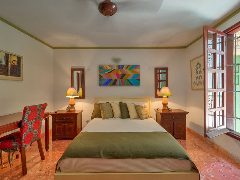 Cozy bedroom with warm lighting and colorful artwork above the bed.