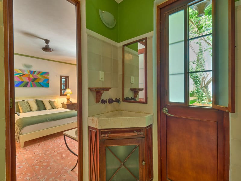 Cozy bedroom with green accents, a wooden door, and a corner mirror.