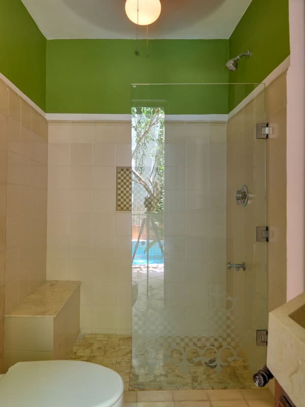 Modern shower with green ceiling and glass partition.