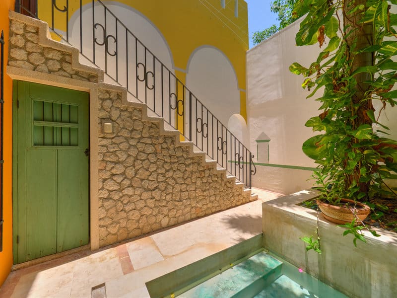 Serene courtyard with stone stairs, green door, and small water feature.