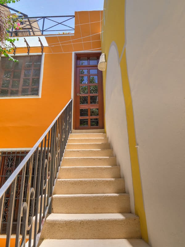 Staircase leading to a door between orange and beige walls.