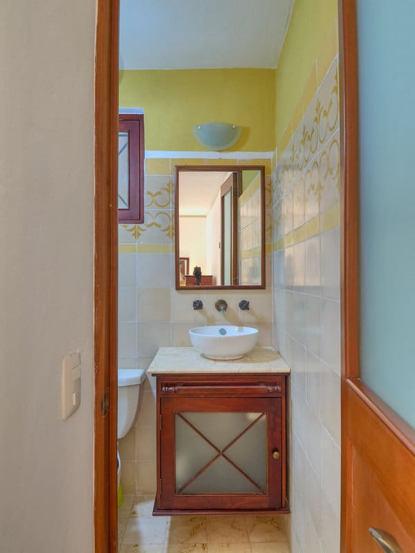 Cozy bathroom with a wooden vanity and a round mirror.