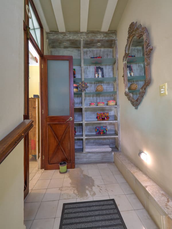 A hallway with shelves filled with decorative items and a large ornate mirror.