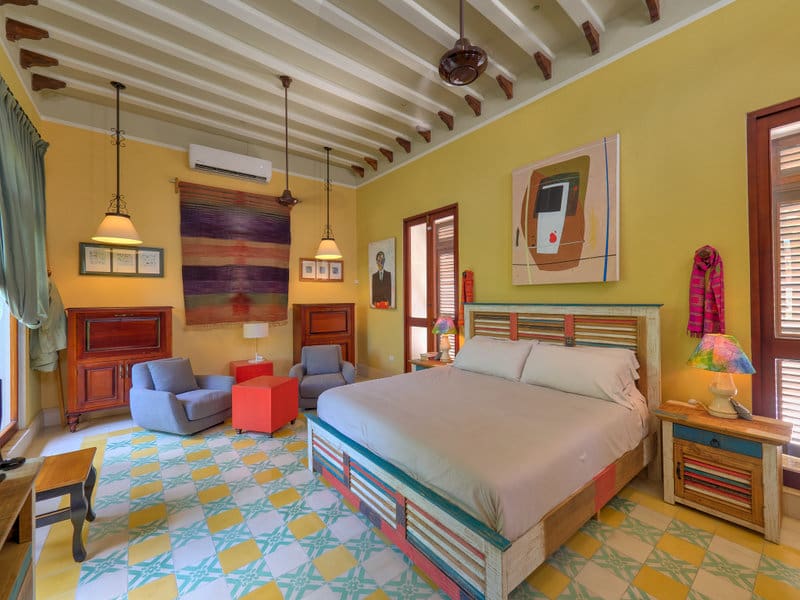 Cozy, colorful bedroom with patterned floor and artistic wall decor.