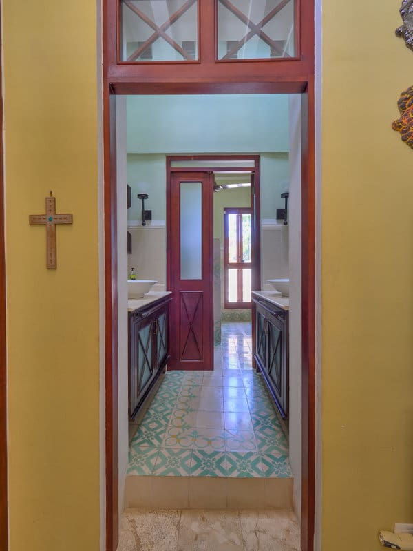 A hallway view through multiple doorways with a cross on the left wall.
