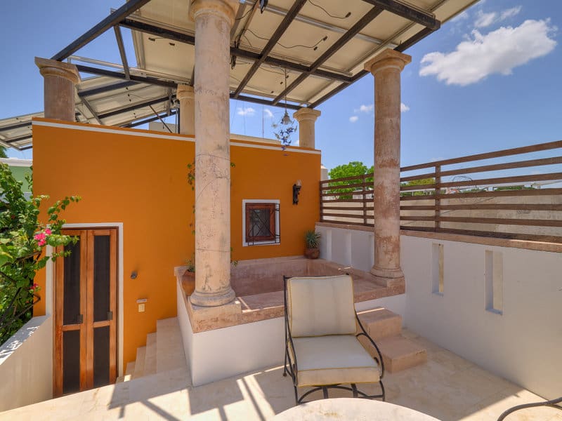 Cozy outdoor patio with orange walls and comfortable seating under a covered roof.