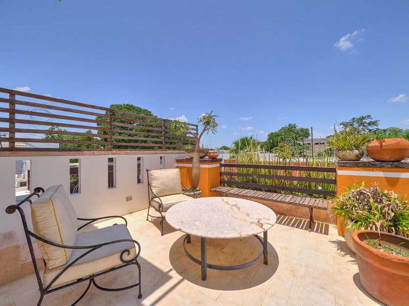 Sunny patio with round table and chairs overlooking greenery.